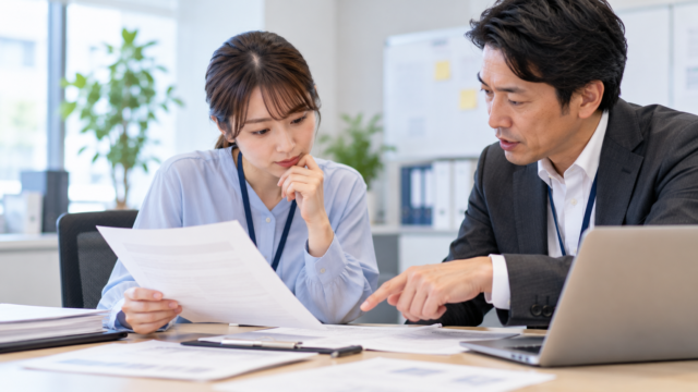 採用担当者と男性社員が応募書類を確認し、生成AIへの情報入力について話し合う様子